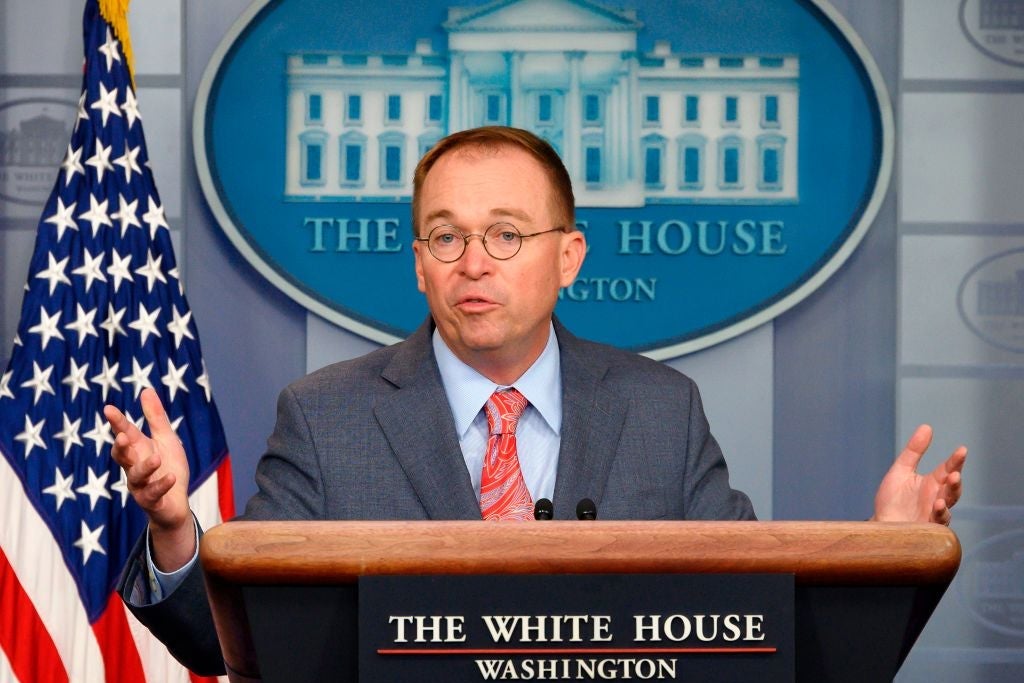 Mulvaney gestures while standing at a lectern in the White House briefing room.