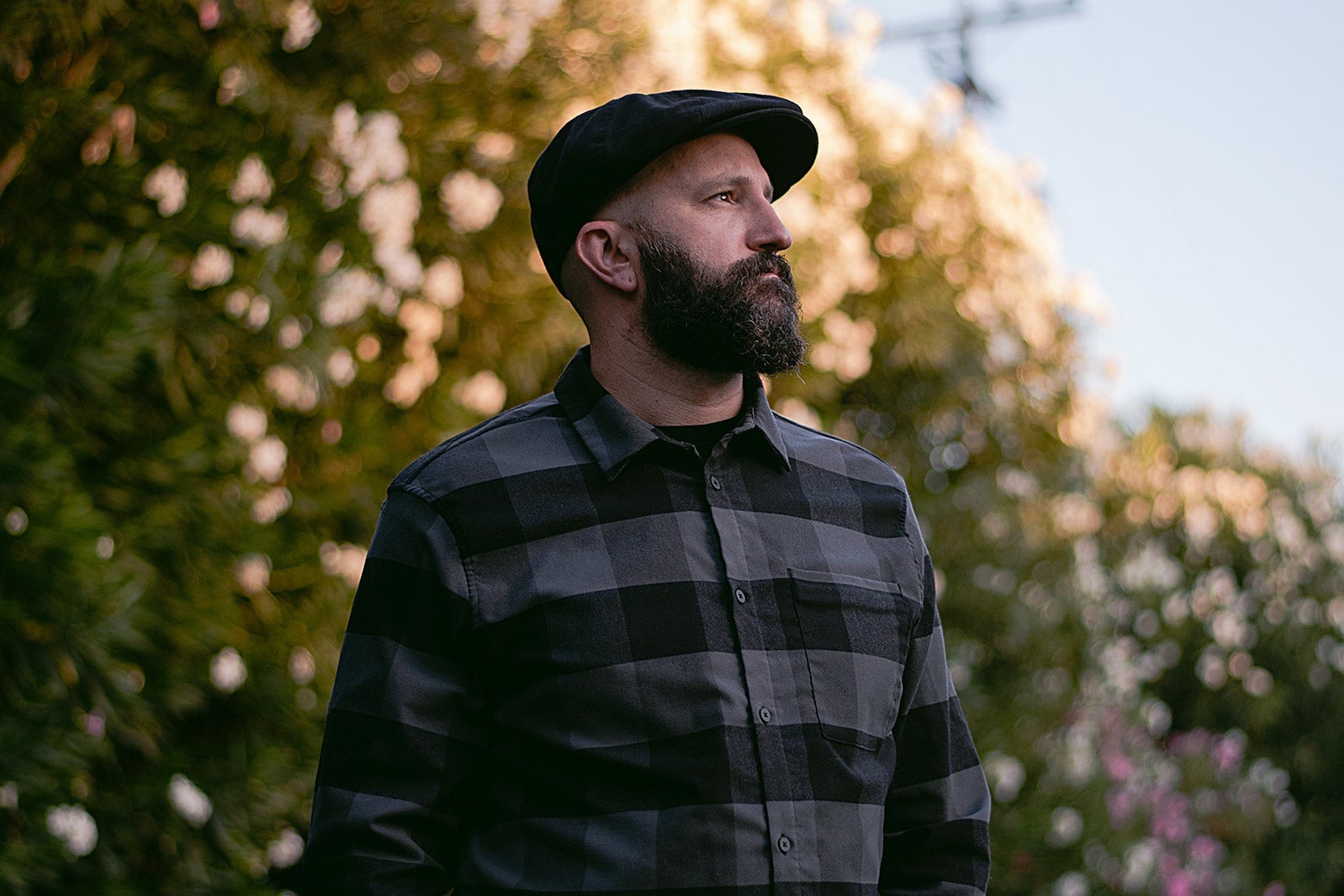 Bearded man standing in front of trees on a sunny day