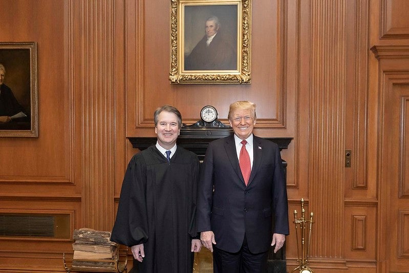 Brett Kavanaugh and Donald Trump smile widely at the Supreme Court.