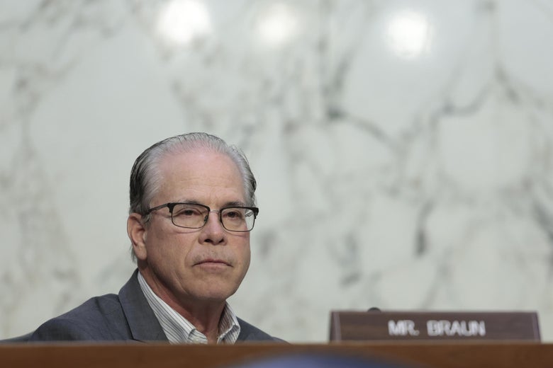 Braun in glasses sitting behind his nameplate in a Senate hearing room