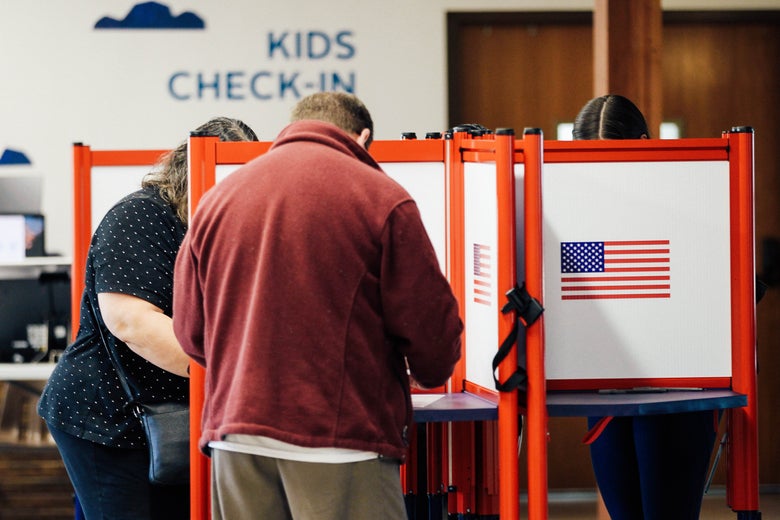 Two people lean over a voting station in a voting hall in Louisville, Kentucky.