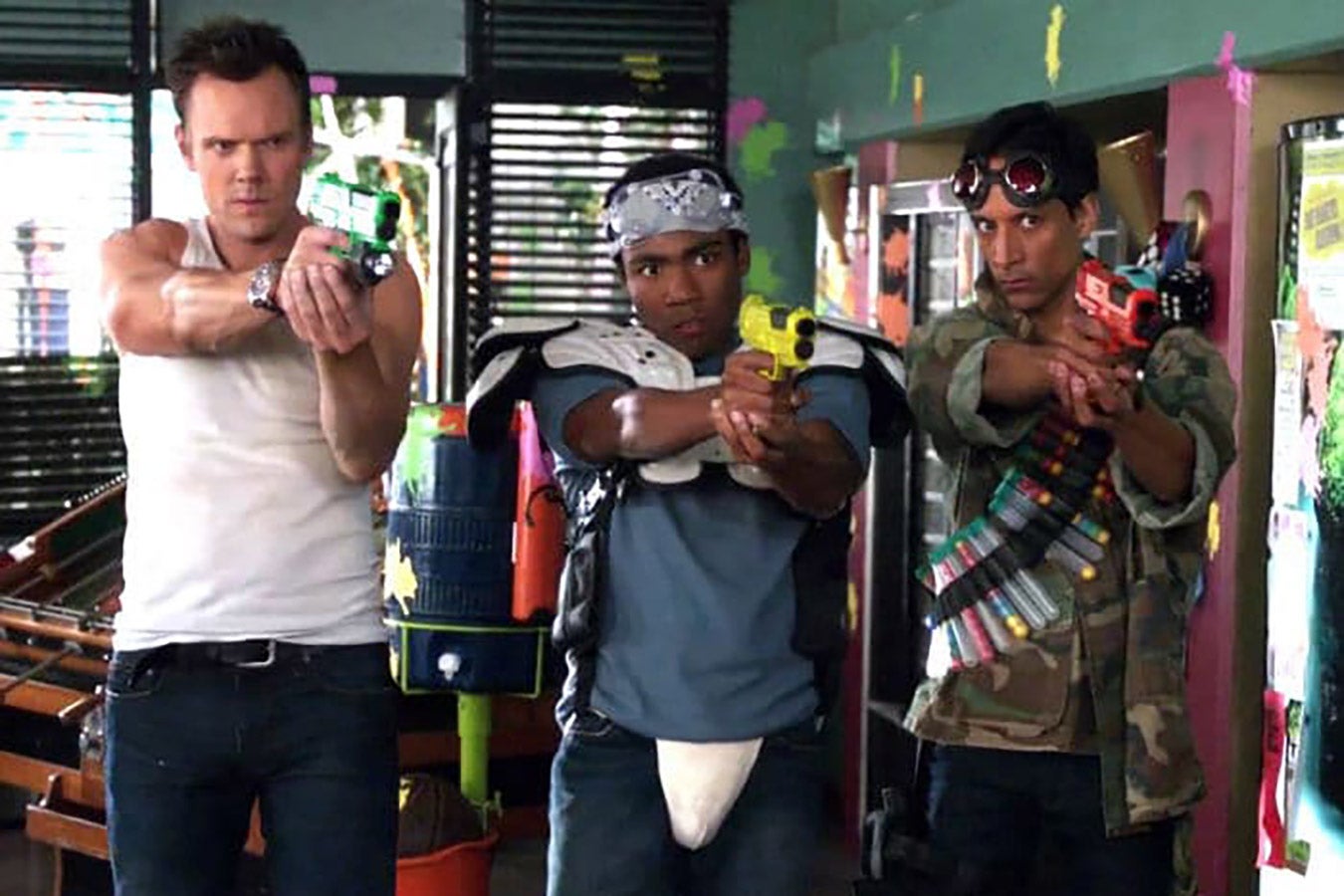 Jeff, Troy, and Abed look intensely ahead and put their makeshift guns at the camera.