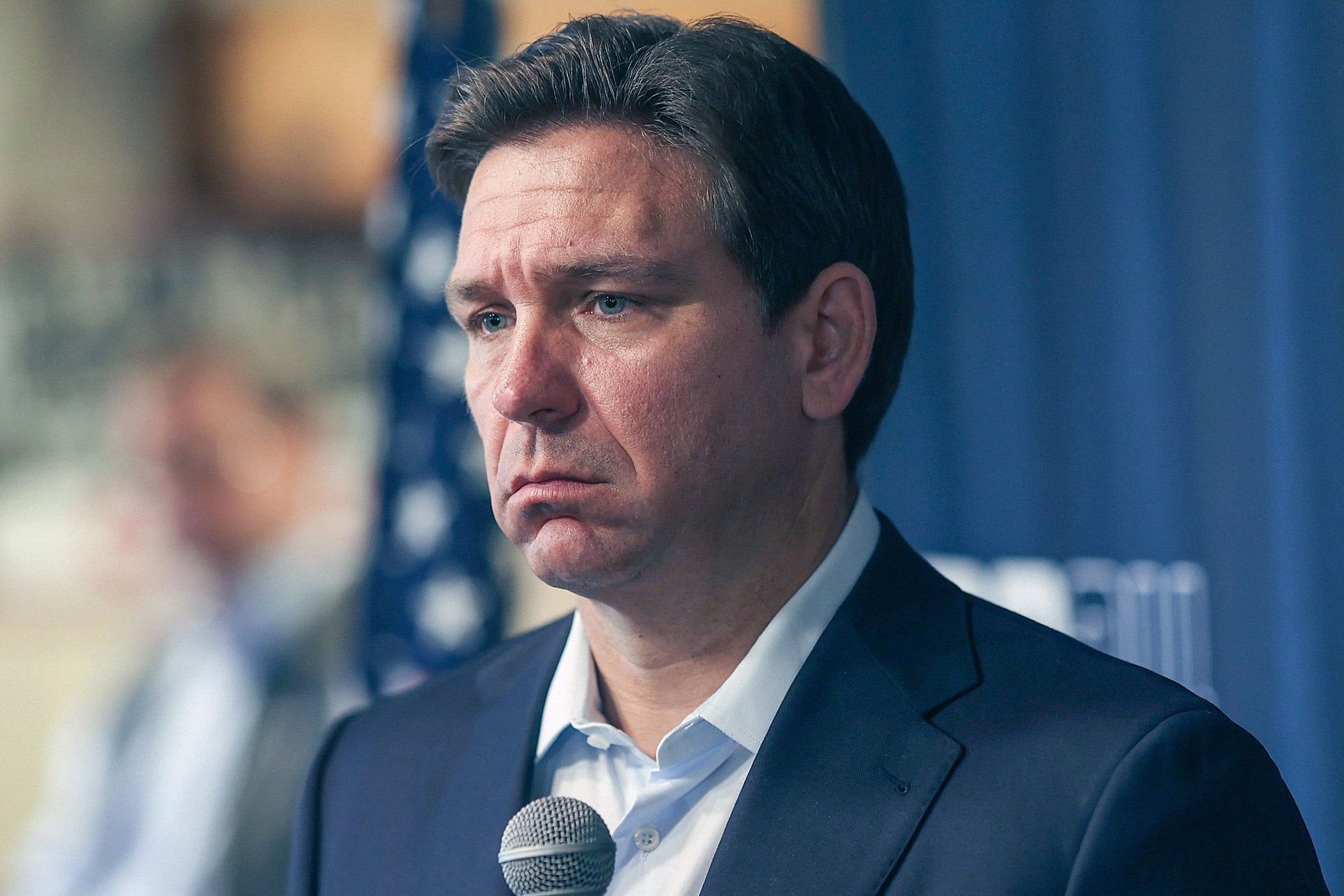 DeSantis frowning like a very sad sack with an unbuttoned collared shirt.