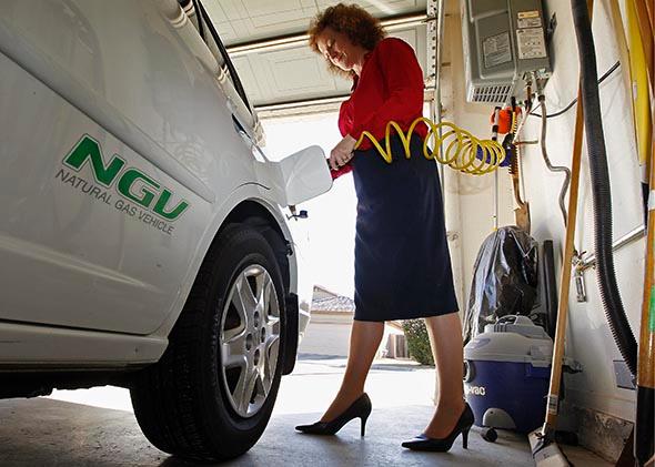 Connie Jones connects the nozzle of a home refueling station to her 2003 natural gas powered Honda Civic in the garage of her home in Chandler, Arizona, October 3, 2013. 