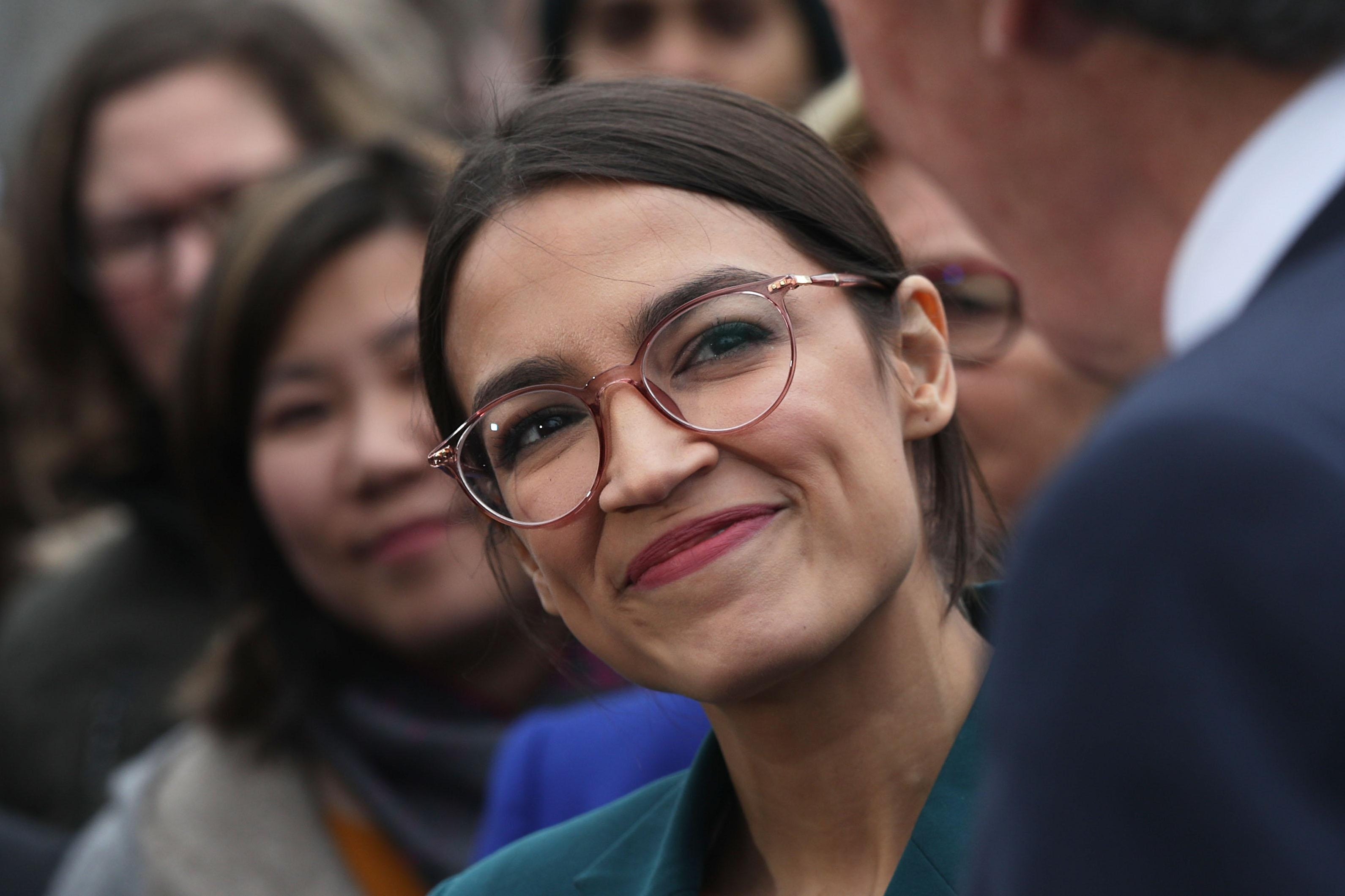 Rep. Alexandria Ocasio-Cortez smiles at her Green New Deal co-author Sen. Ed Markey during a Capitol Hill news conference.