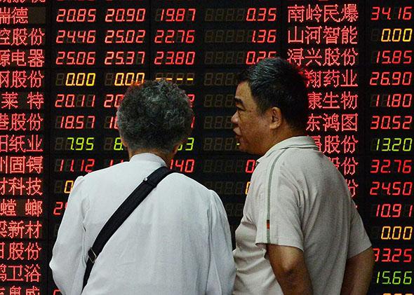 Investors talk in front of a board displaying share prices at a security firm in Shanghai on July 1, 2015. Shanghai shares closed down more than five percent on July 1, resuming their downward trajectory a day after recording their biggest gains in more than six years.    
