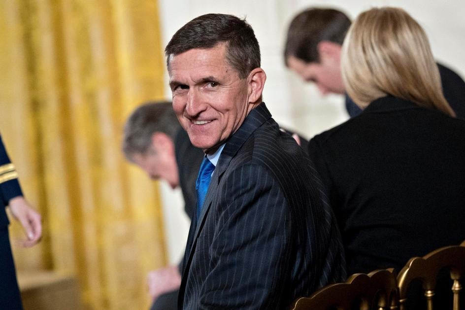 Michael Flynn turns around and smiles while seated in a chair.