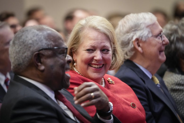 Justice Clarence Thomas sits with his wife and conservative activist Virginia Thomas while he waits to speak at the Heritage Foundation on October 21, 2021 in Washington, DC. next to Mitch McConnell. All are laughing.