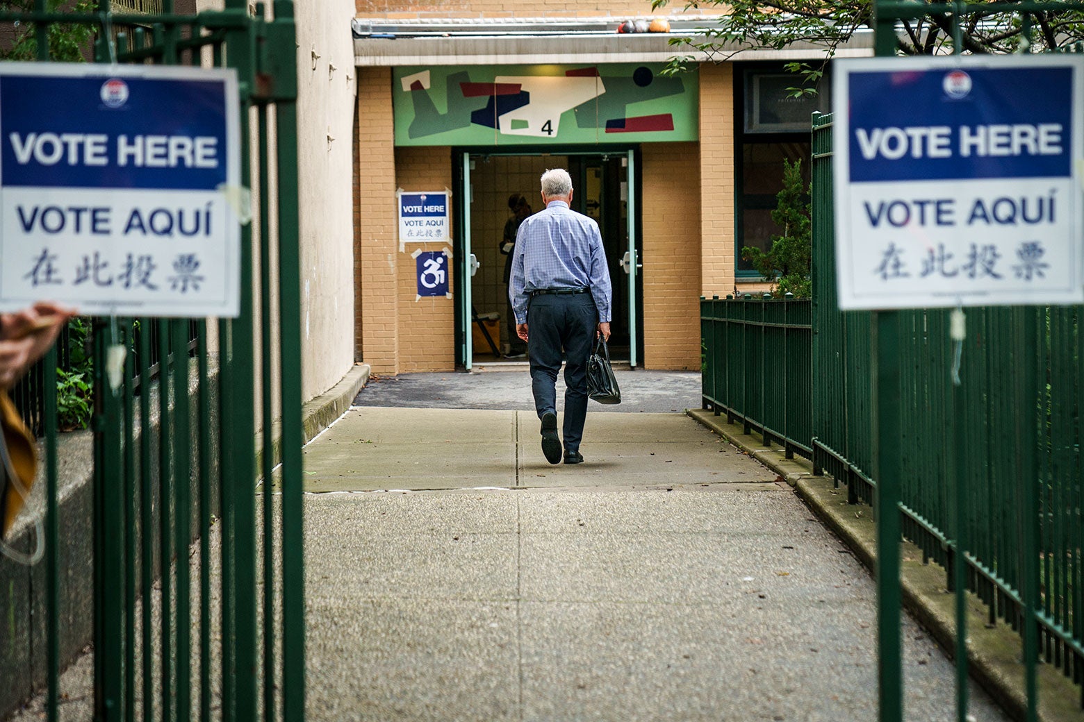 A voter enters a Brooklyn polling station on Thursday to vote in New York state’s primary election. The signs saying "vote here" are listed in English, Spanish, and Japanese.