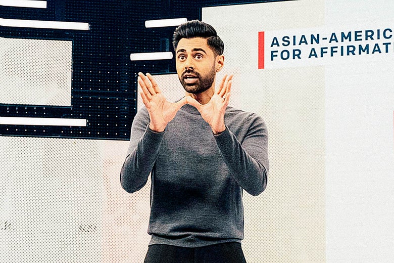 Hasan Minhaj on stage with a chart.