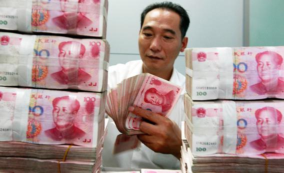 A Chinese bank worker counts stacks of 100-yuan notes at a bank.