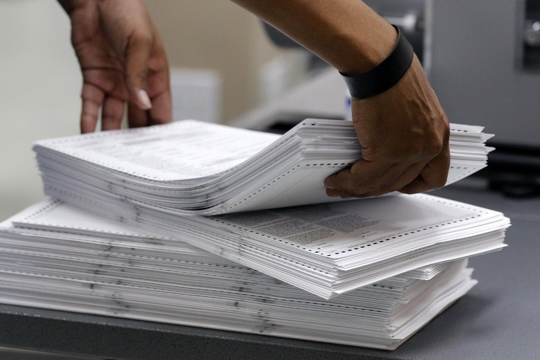 A pair of hands picking up a stack of ballots.