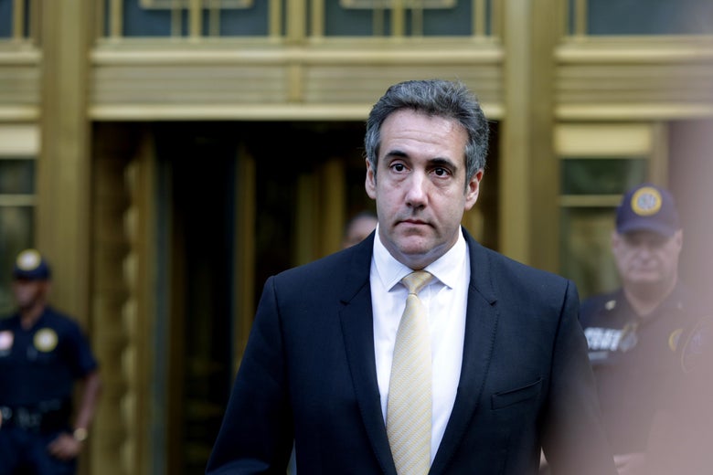 Michael Cohen walks away from a courthouse, with police officers behind him.