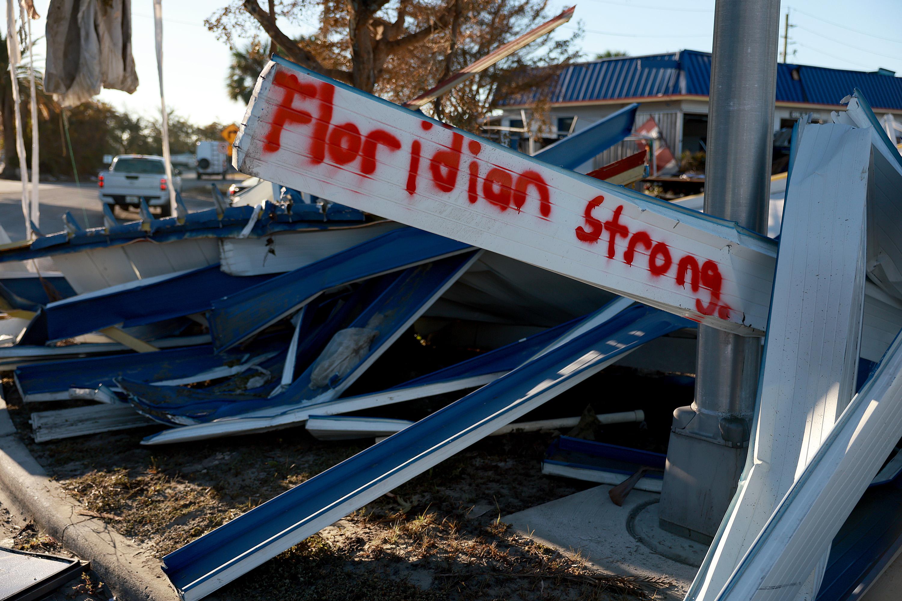 A spray-painted sign reading "Floridian Strong" lies among debris.