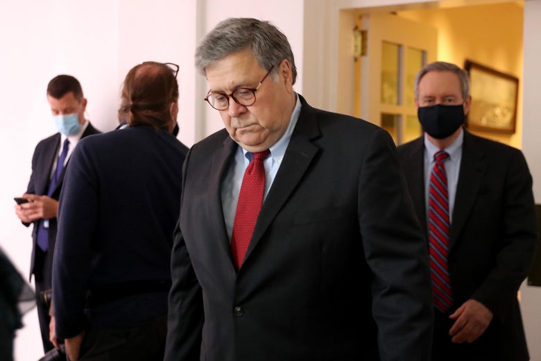 Barr wearing a red tie and looking down at his shoes.