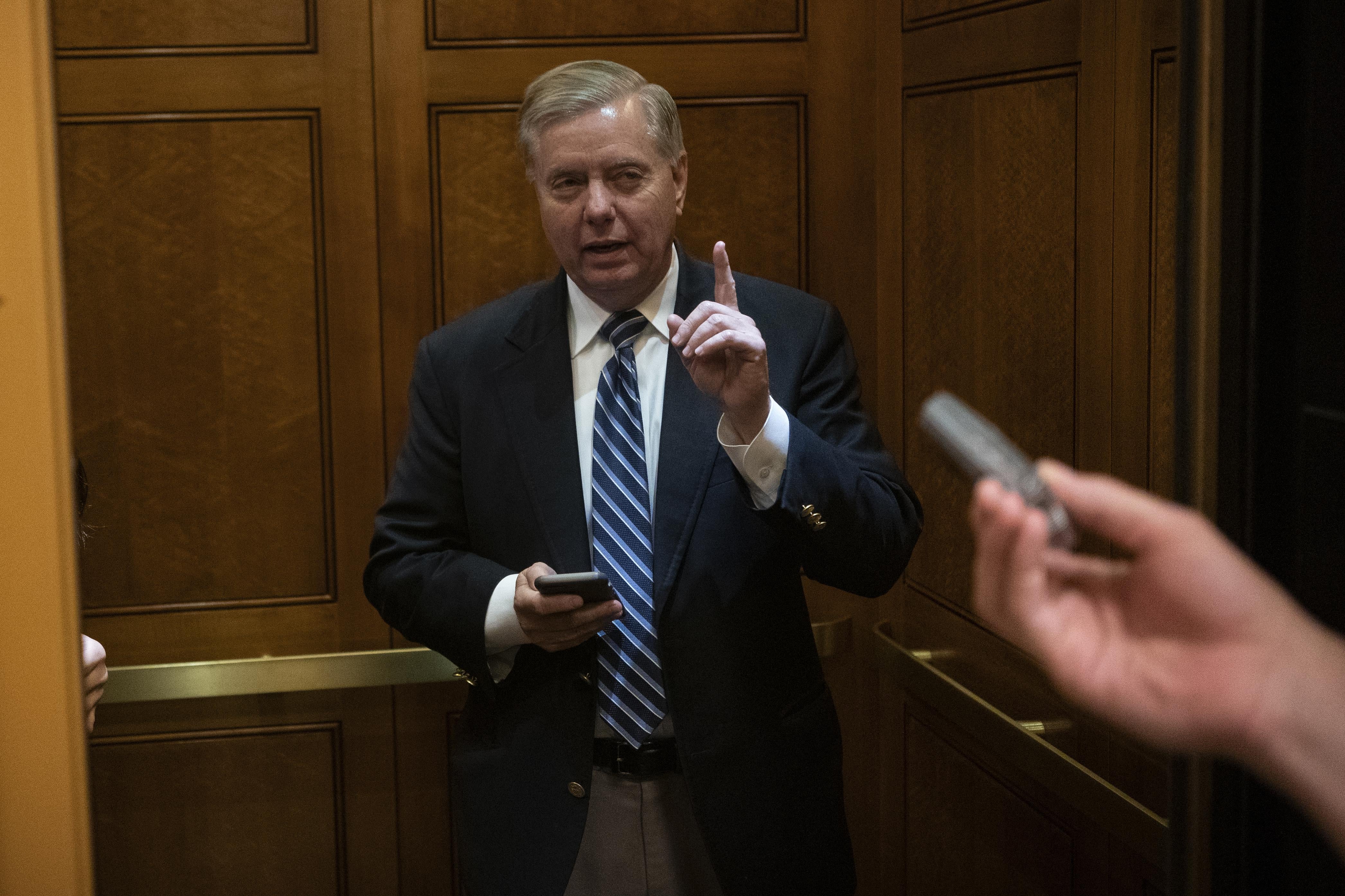 Lindsey Graham speaks to reporters while getting on an elevator.