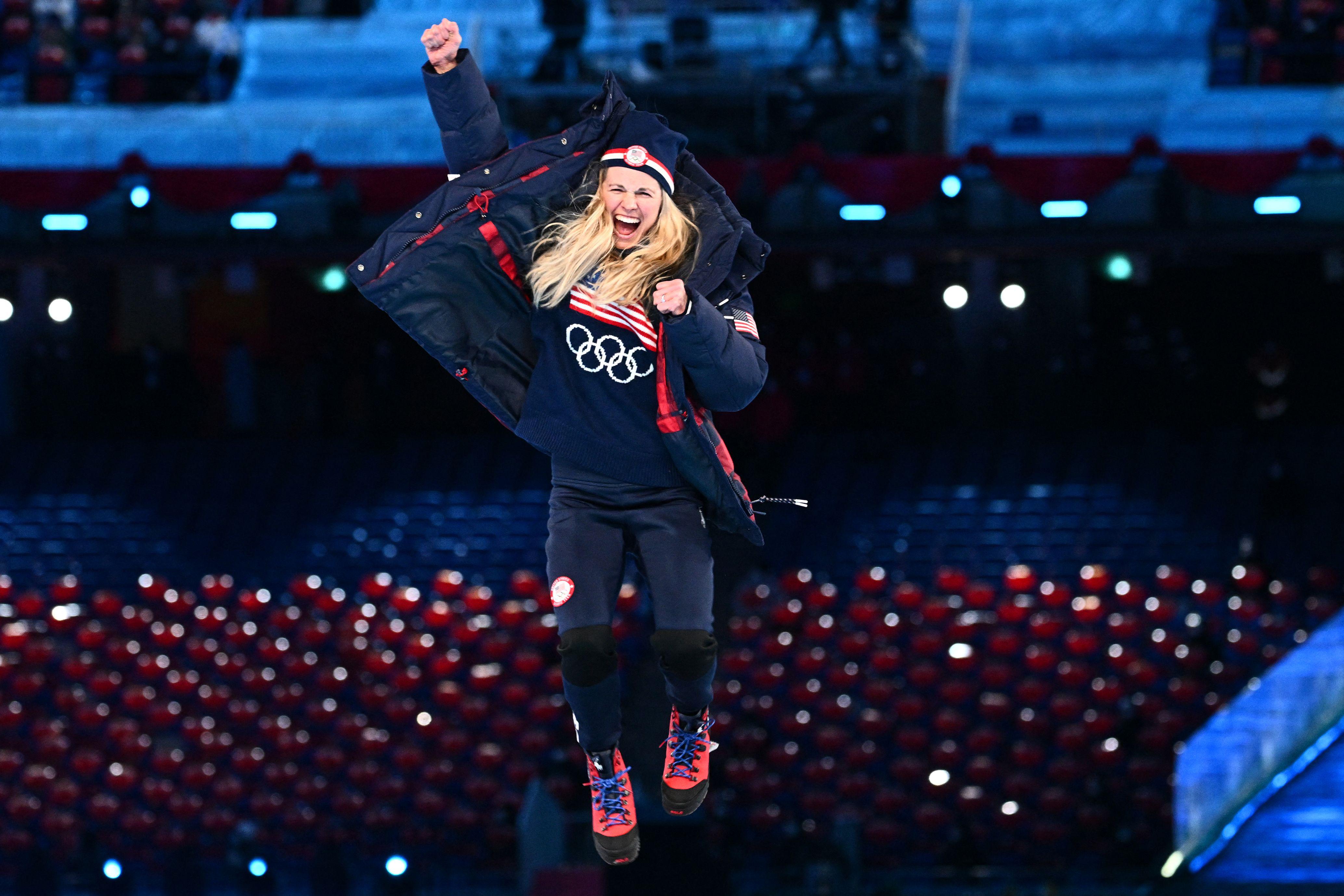 Diggins jumps in the air, pumps her fist, beaming, clutching her silver medal, in hat and puffy coat