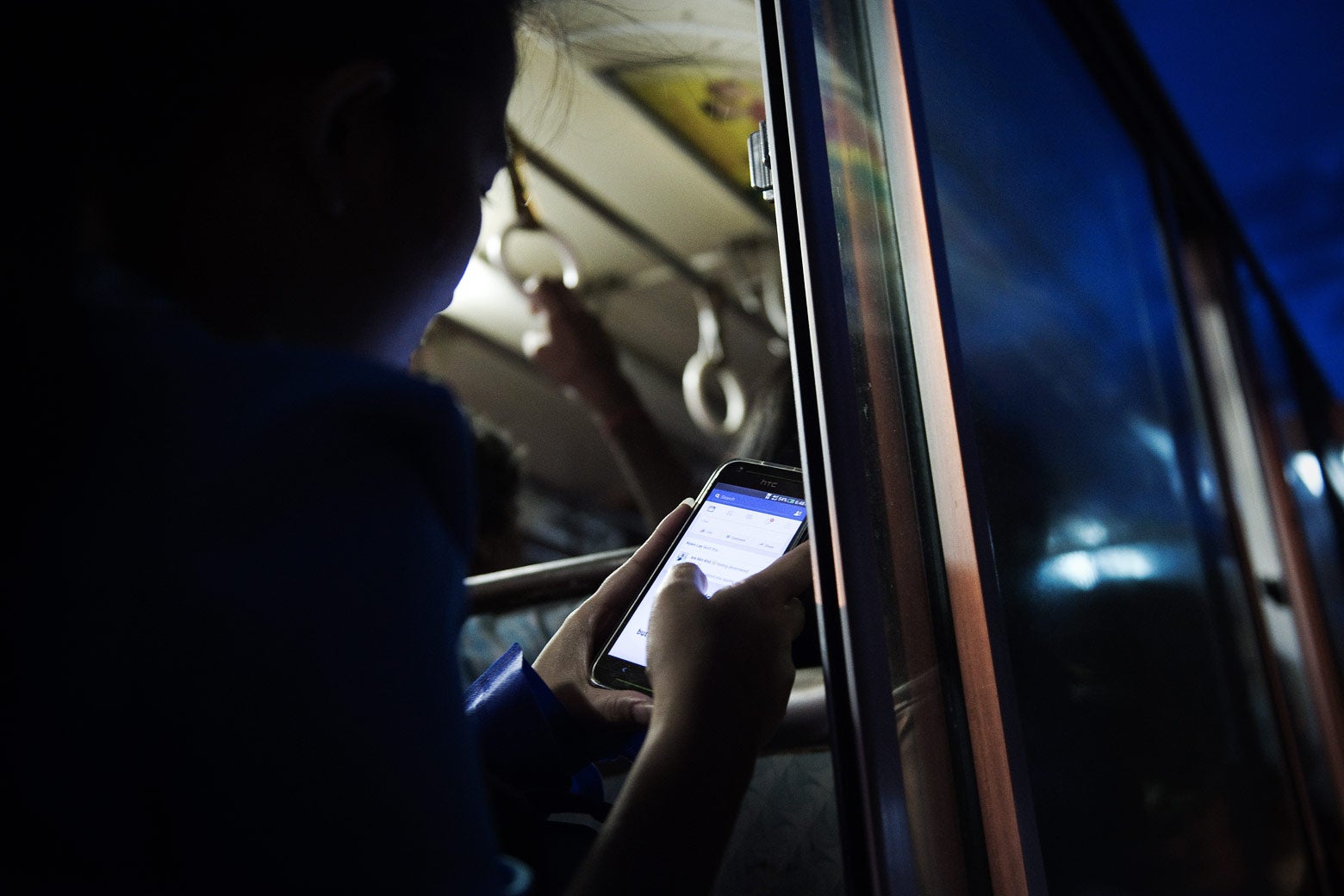 A young woman looks at Facebook while she travels on a bus in Yangon, Myanmar, in 2015. 