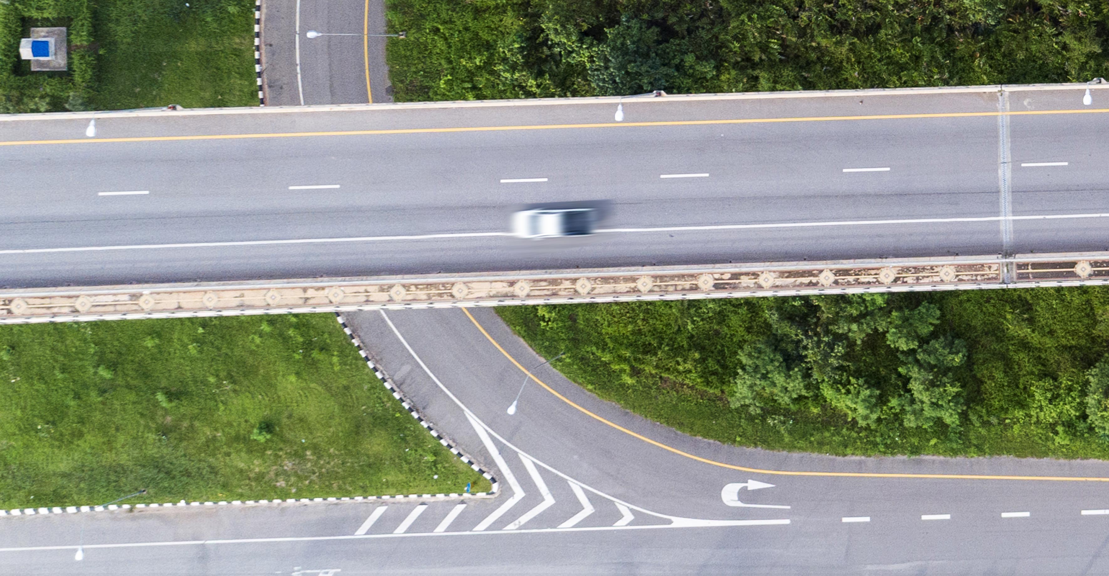 A blurry car seen from overhead as it drives down an empty highway.