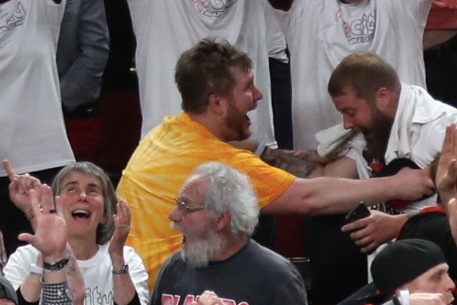 A bearded fan in a yellow shirt embraces a friend with a look of what can only be described as ecstatic spiritual fulfillment.