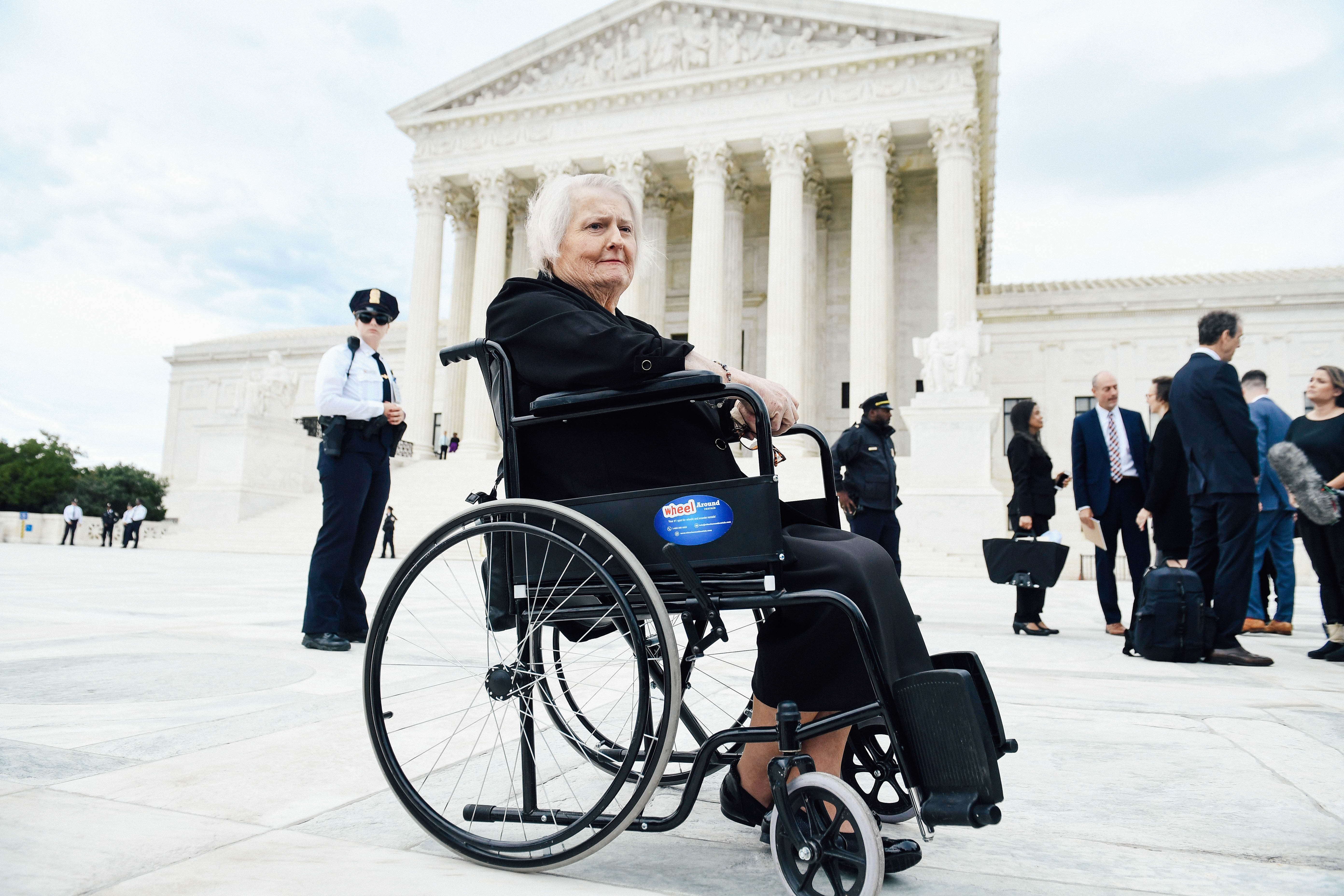 Aimee Stephens sitting in a wheelchair outside the Supreme Court building.