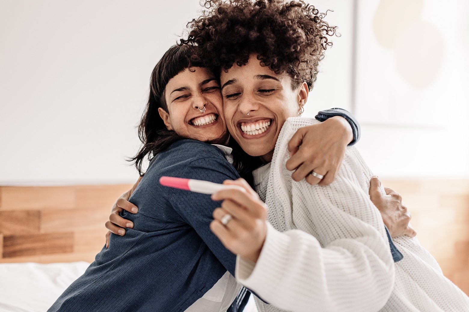 A happy same-sex couple looking at a positive pregnancy test.