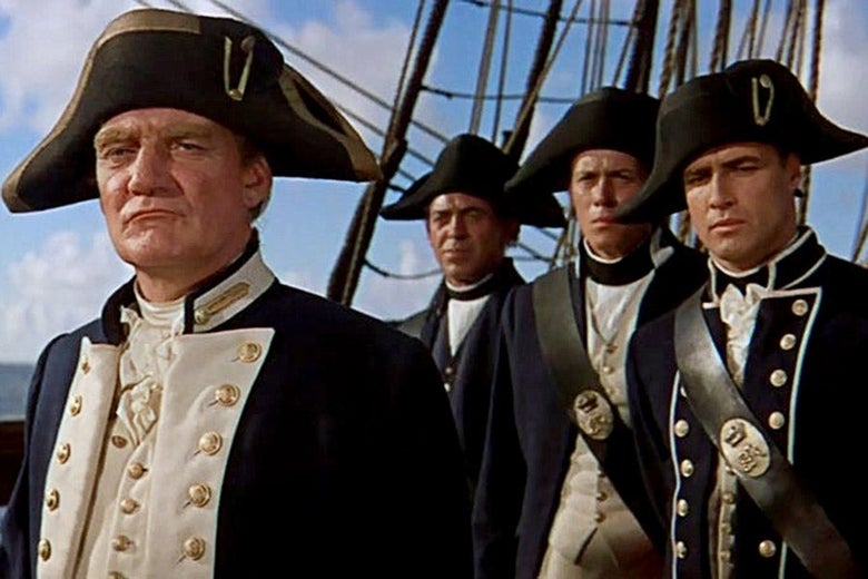 Capt. Bligh stands in the foreground, looking self-satisfied, as a Brando’s Fletcher Christian looks on skeptically