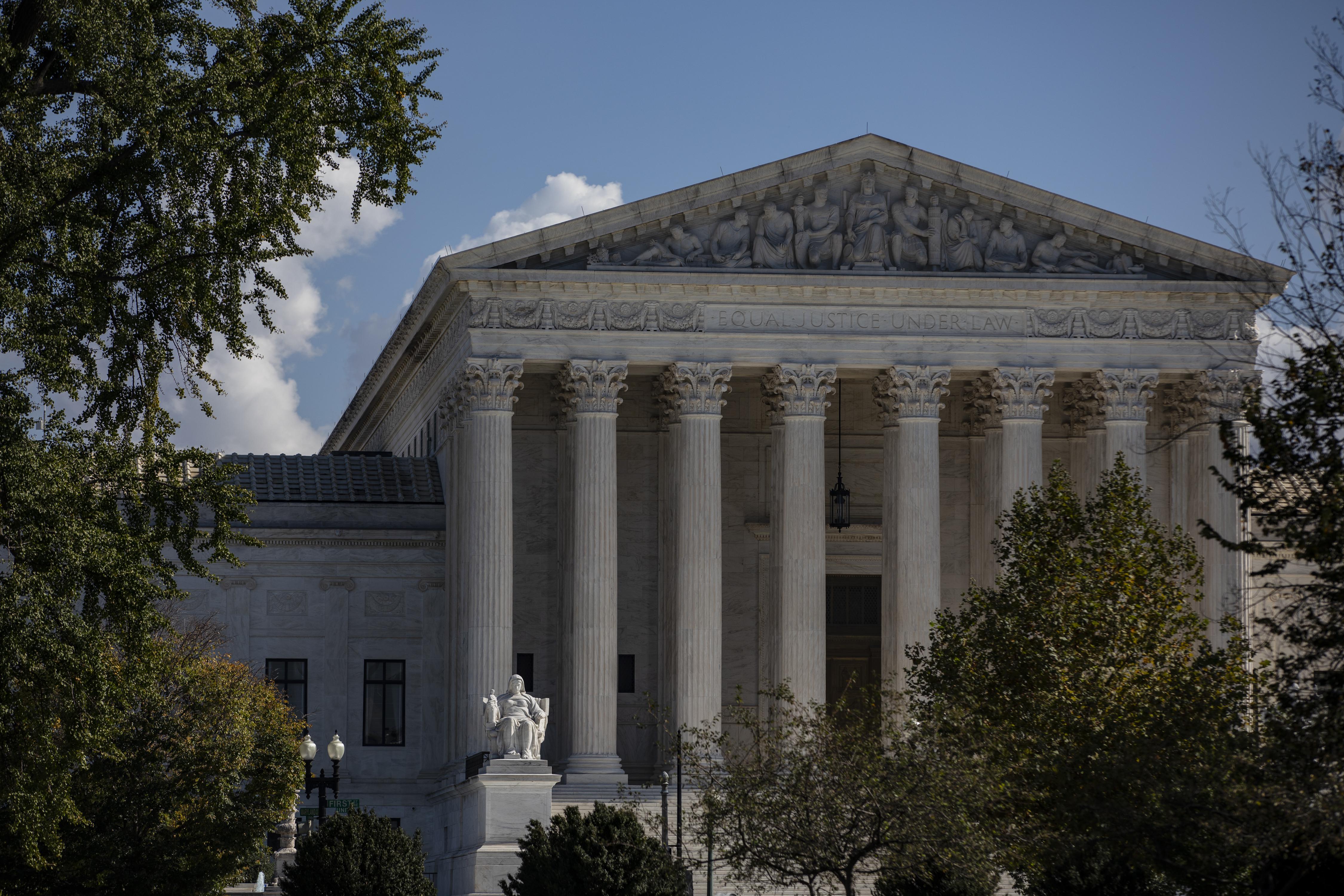 Trees on each side form the foreground of this image of the Supreme Court building with its grand columns.
