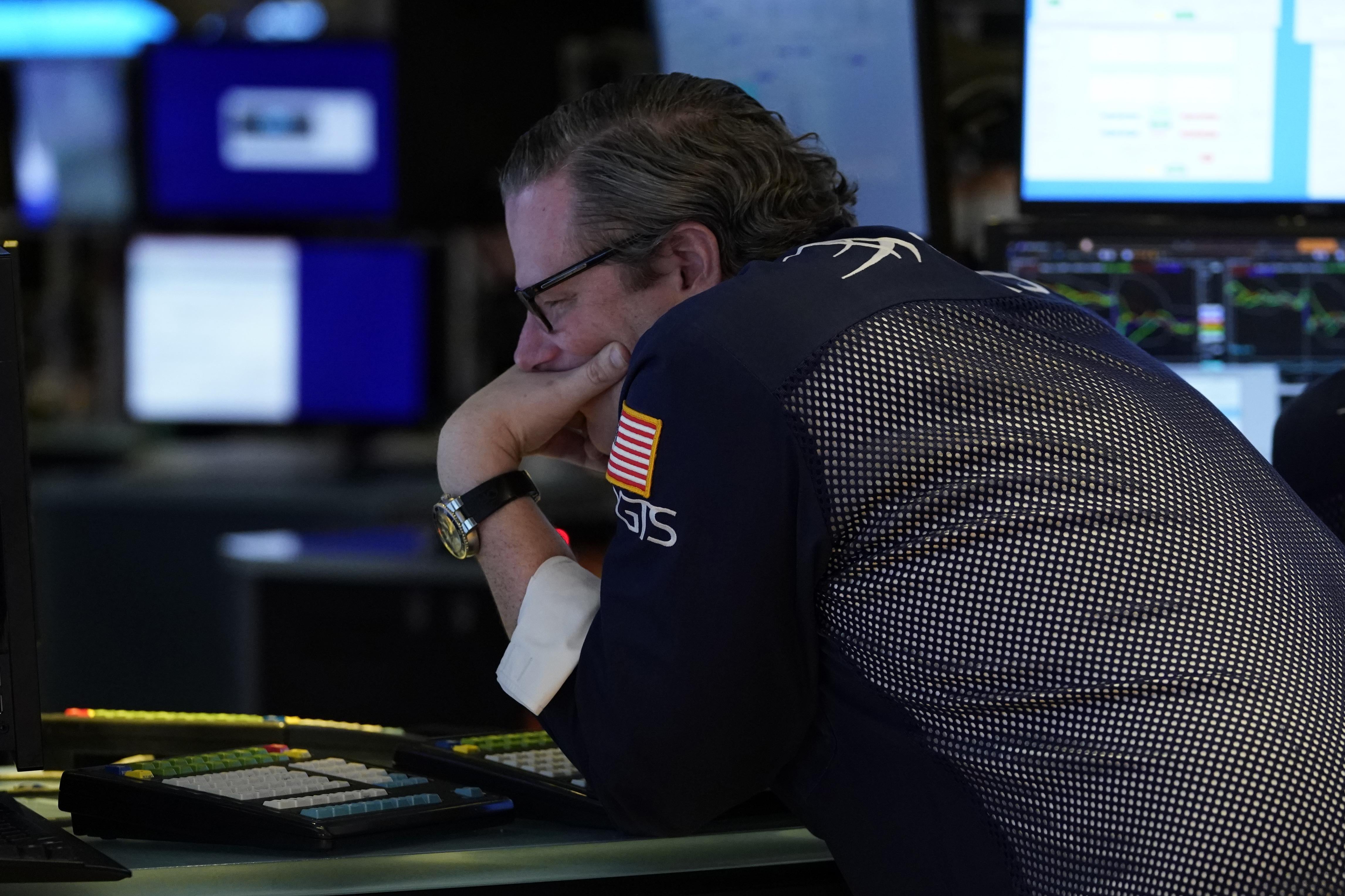 A trader hunches over a keyboard with his hand over his mouth