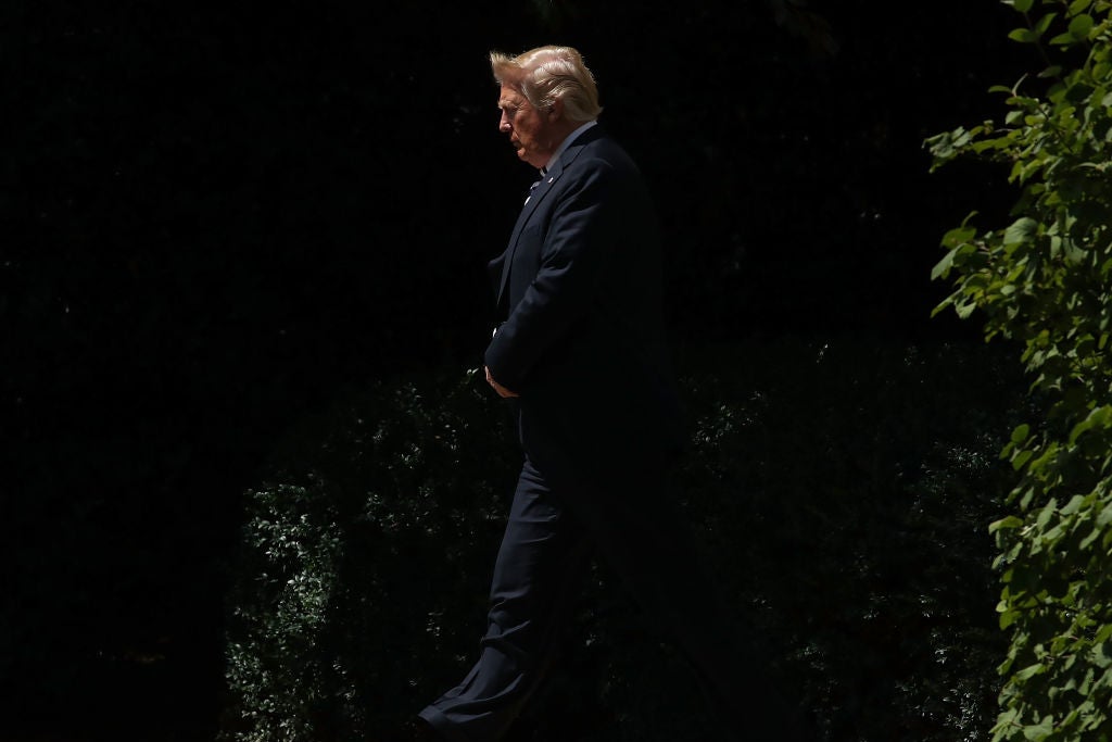 Trump walks past some shrubbery.