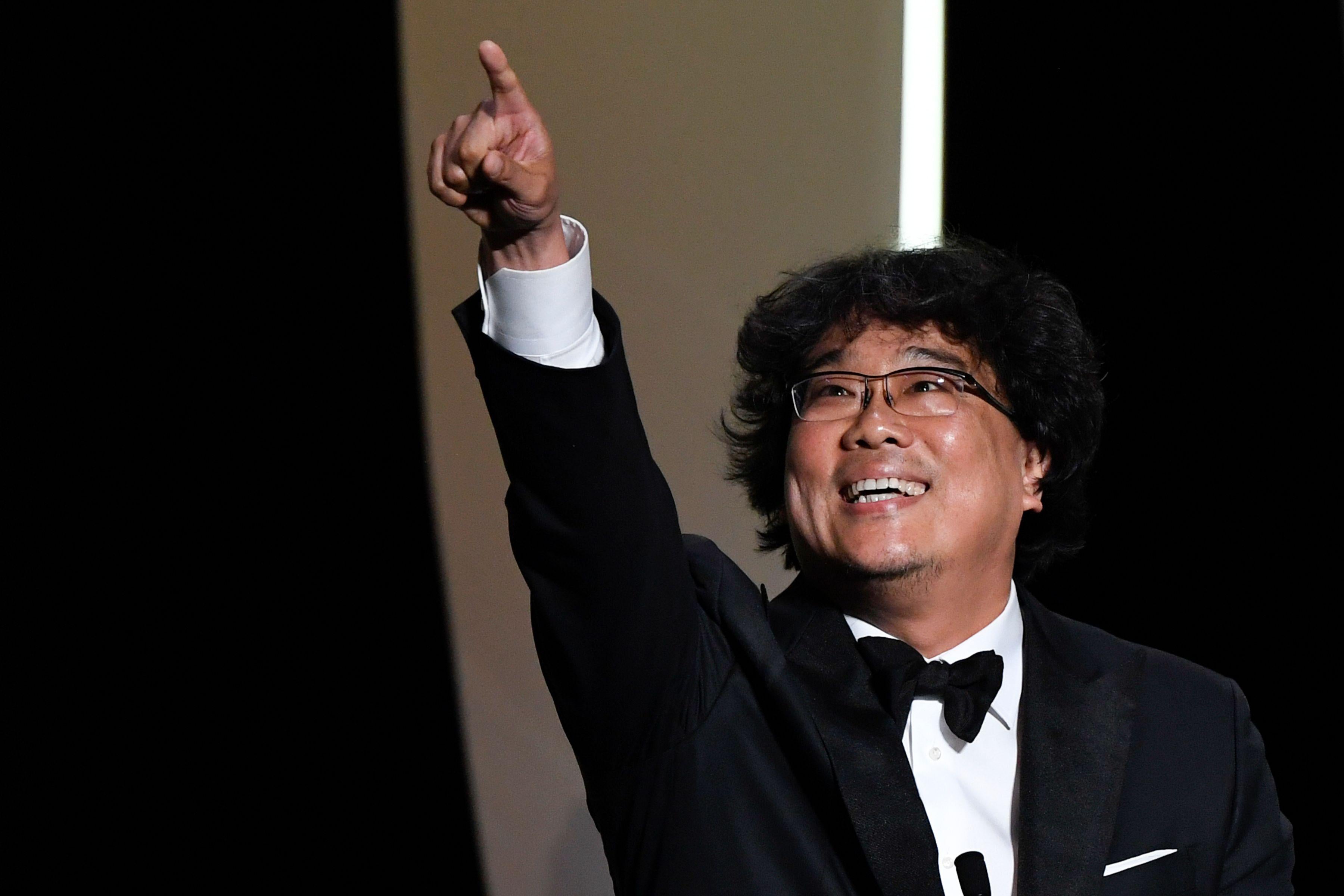 Director Bong Joon-ho smiles and raises his hand in triumph.