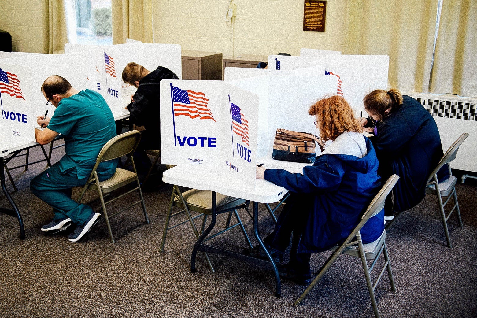 People leaning over to vote while seated at voting booths inside a church in Ohio. 