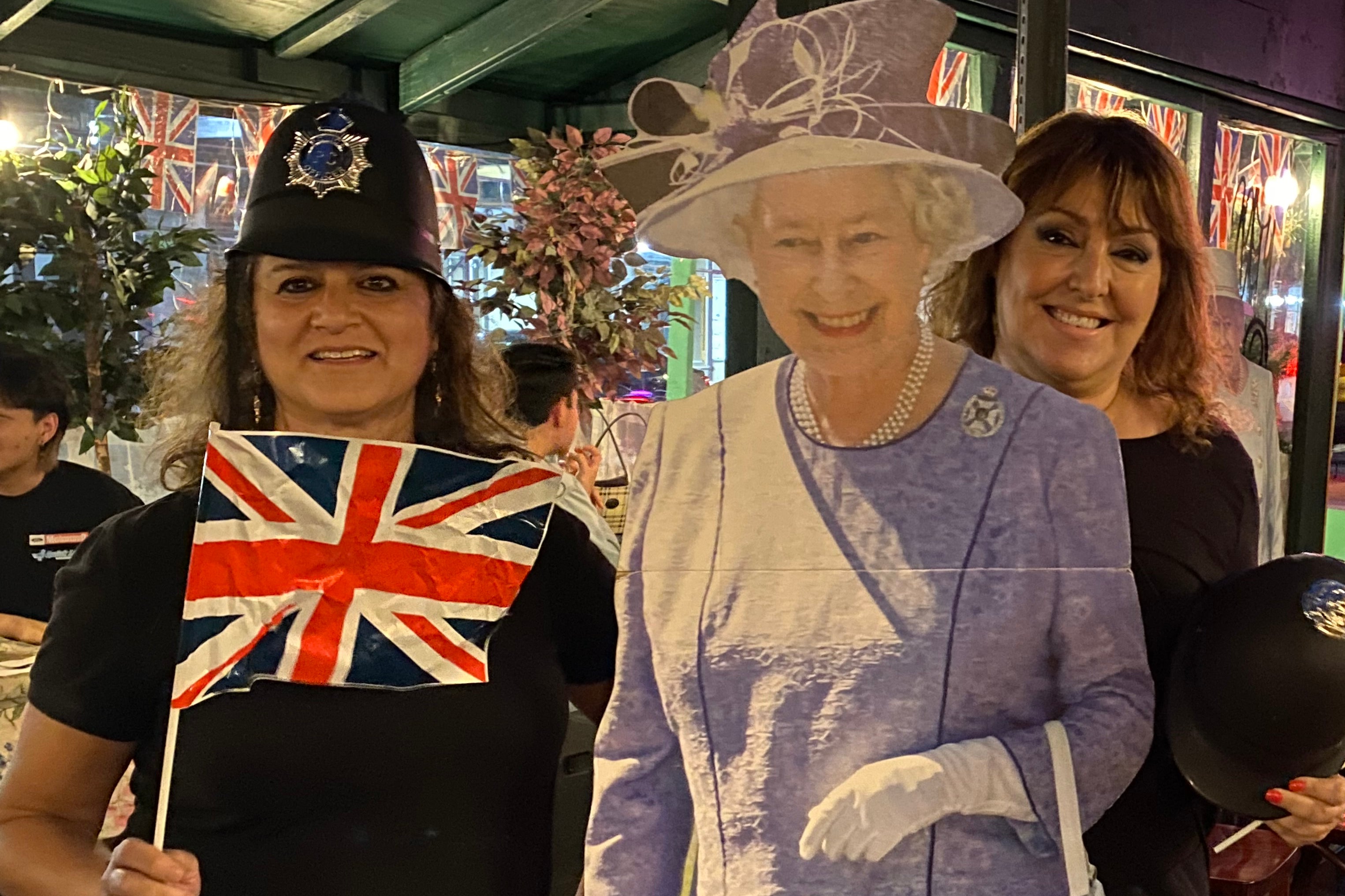 Two women with a life-size cutout of Queen Elizabeth. 