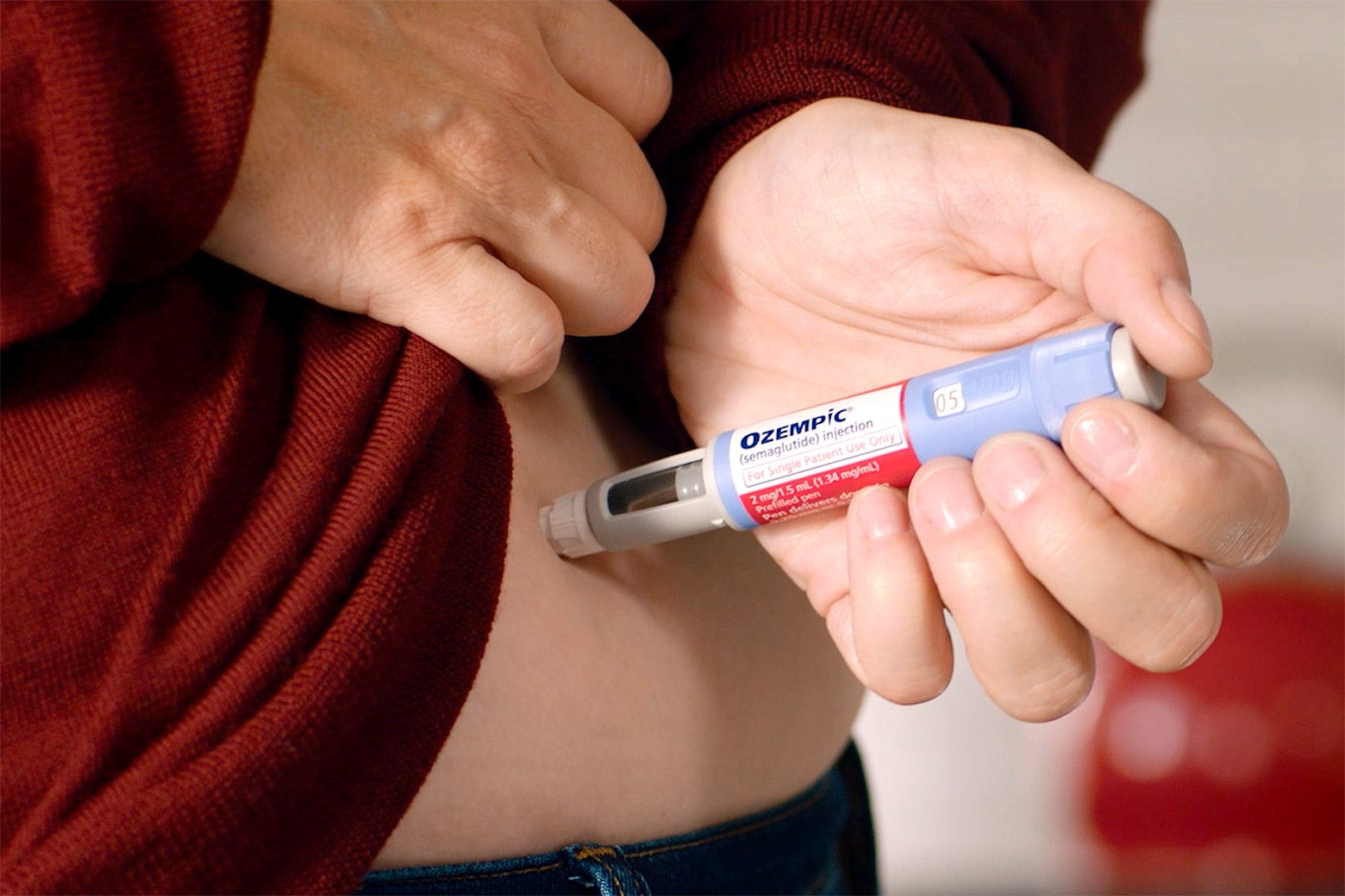 A woman injecting an Ozempic pen into her stomach.