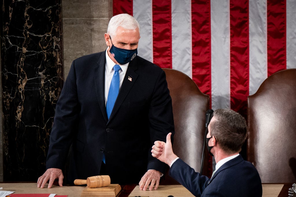 Pence, wearing a black suit and a white tie, stands at the dais in the House chamber against the backdrop of an American flag.