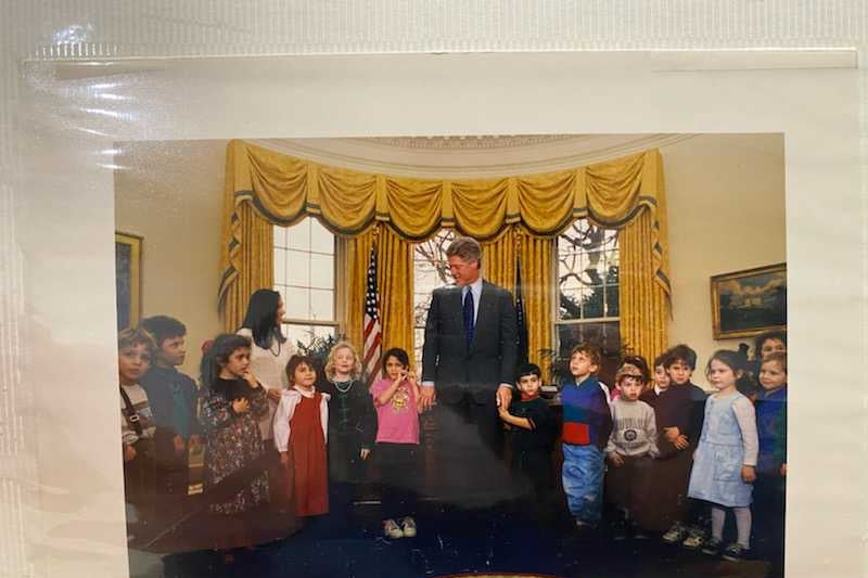 A picture of a page in a family photo album that contains a photo of a bunch of children in the Oval Office with Bill Clinton in 1993.