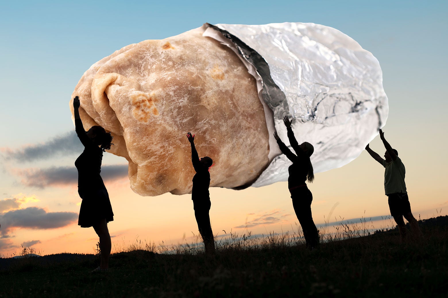 A large burrito wrapped in foil is held up by four silhouetted people. 