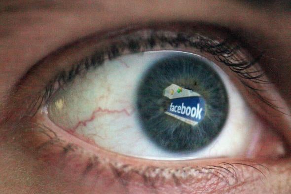 An eyeball with the Facebook logo reflected in it.