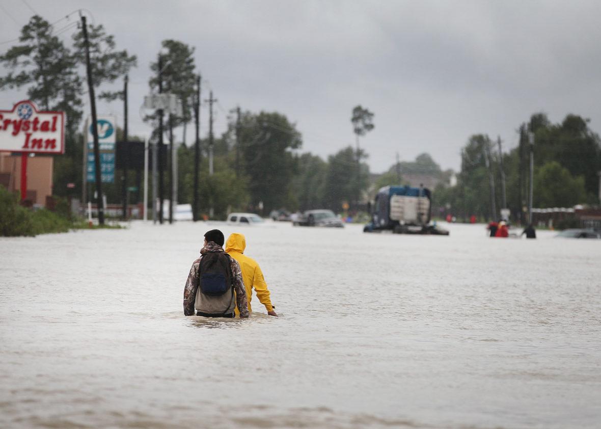 People make their way out of a flooded neighborhood
