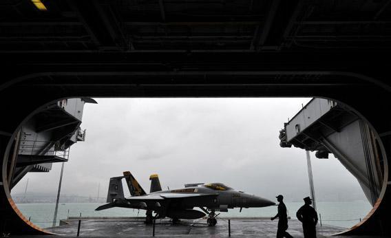 US navy servicemen are seen with an F/A-18 Hornet warplane on the USS George Washington, a nuclear powered aircraft carrier, in Hong Kong on November 9, 2011.