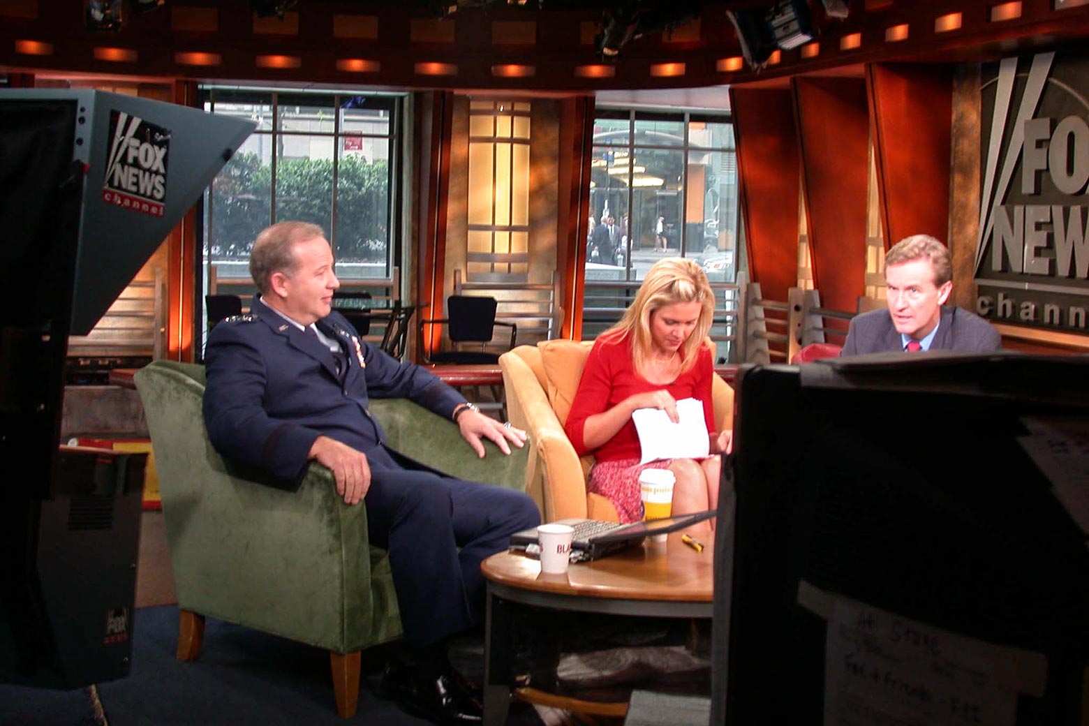 In a photo of an off-the-air moment, E.D. looks through cue cards while Steve chats with a uniformed general, who is the guest. 