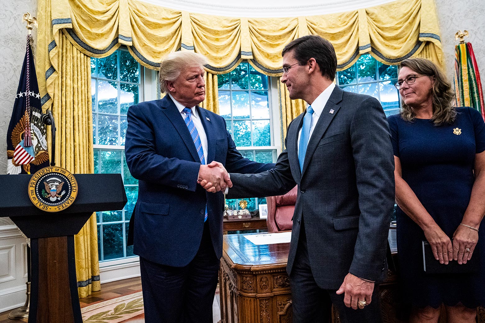 Mark Esper shakes hands with the president as his wife, Leah Esper, looks on.