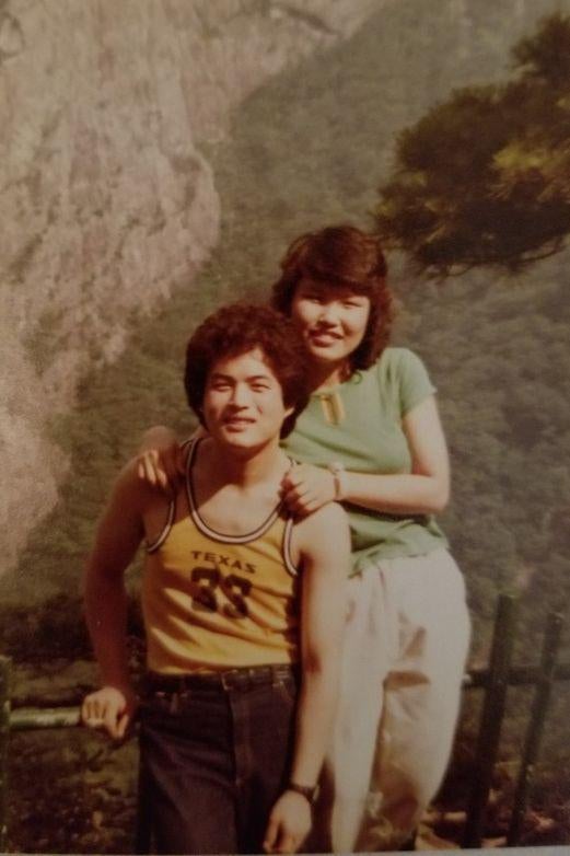 In a faded photograph, woman puts her arms on the shoulders of a man in a basketball jersey.