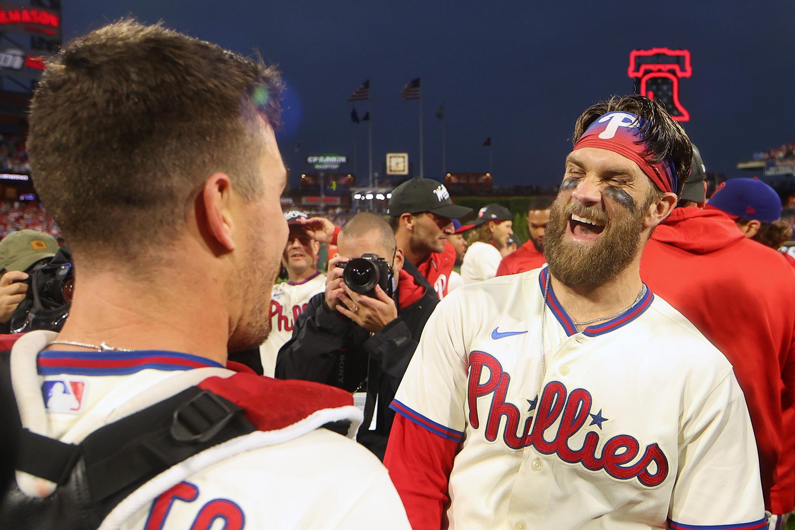 Harper laughs with Realmulto, whose back is turned, as the Phillies crowd around them on the field