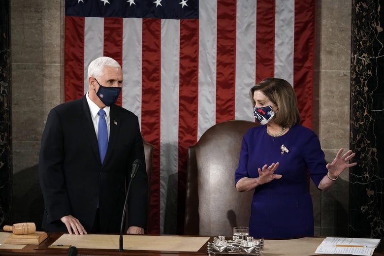 Mike Pence and Nancy Pelosi standing, wearing face masks, and talking at a desk