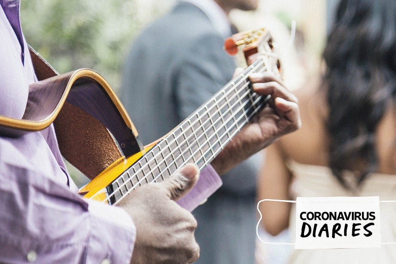 Une personne est vue jouer de la guitare derrière un couple en tenue de mariage. Un masque avec les mots