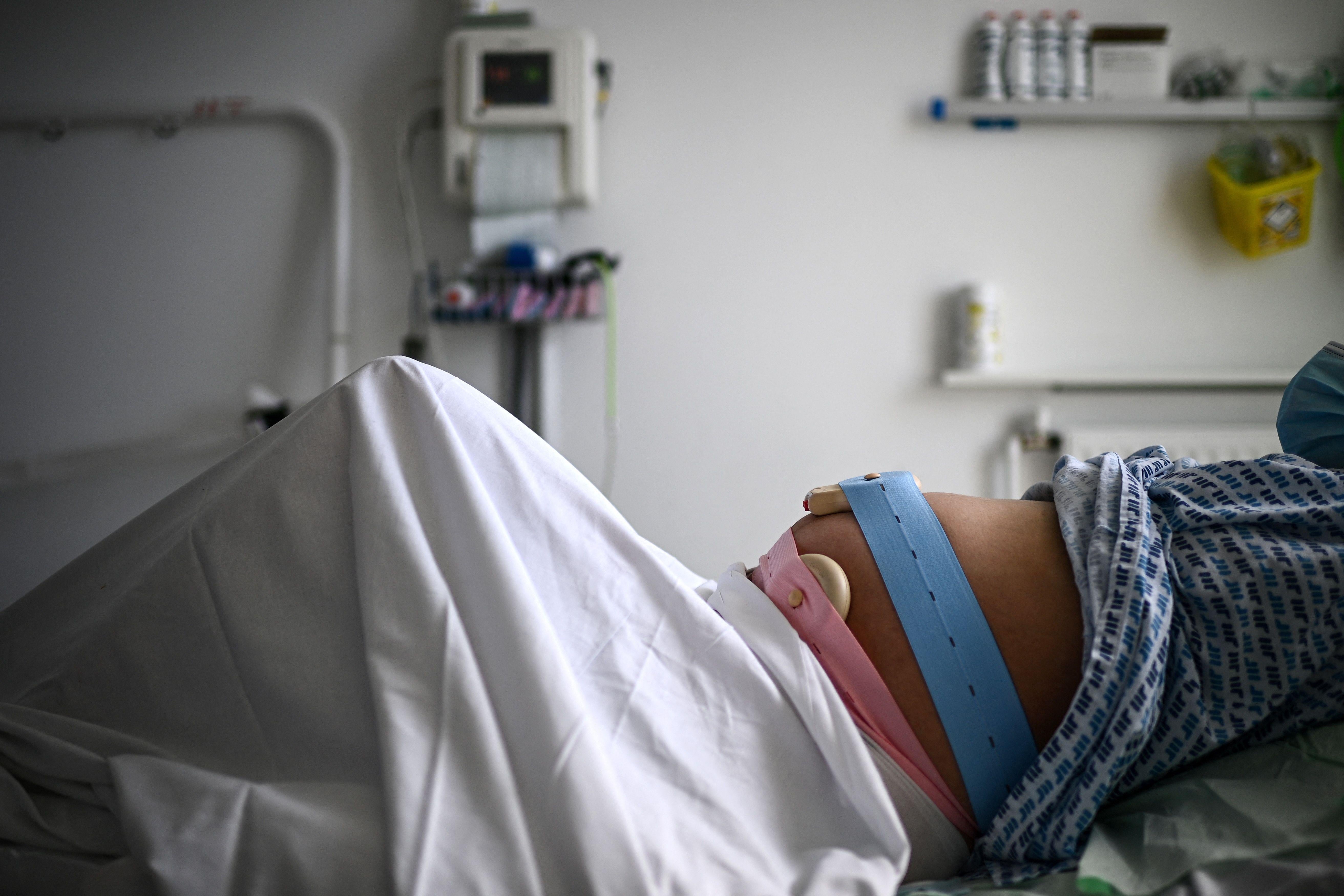 A pregnant woman lying in bed with monitoring devices placed on her belly in the maternity ward of a hospital in Paris