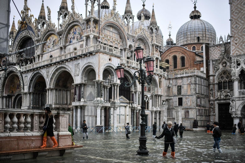 Pedestrians walk across the flooded St. Mark’s Square.