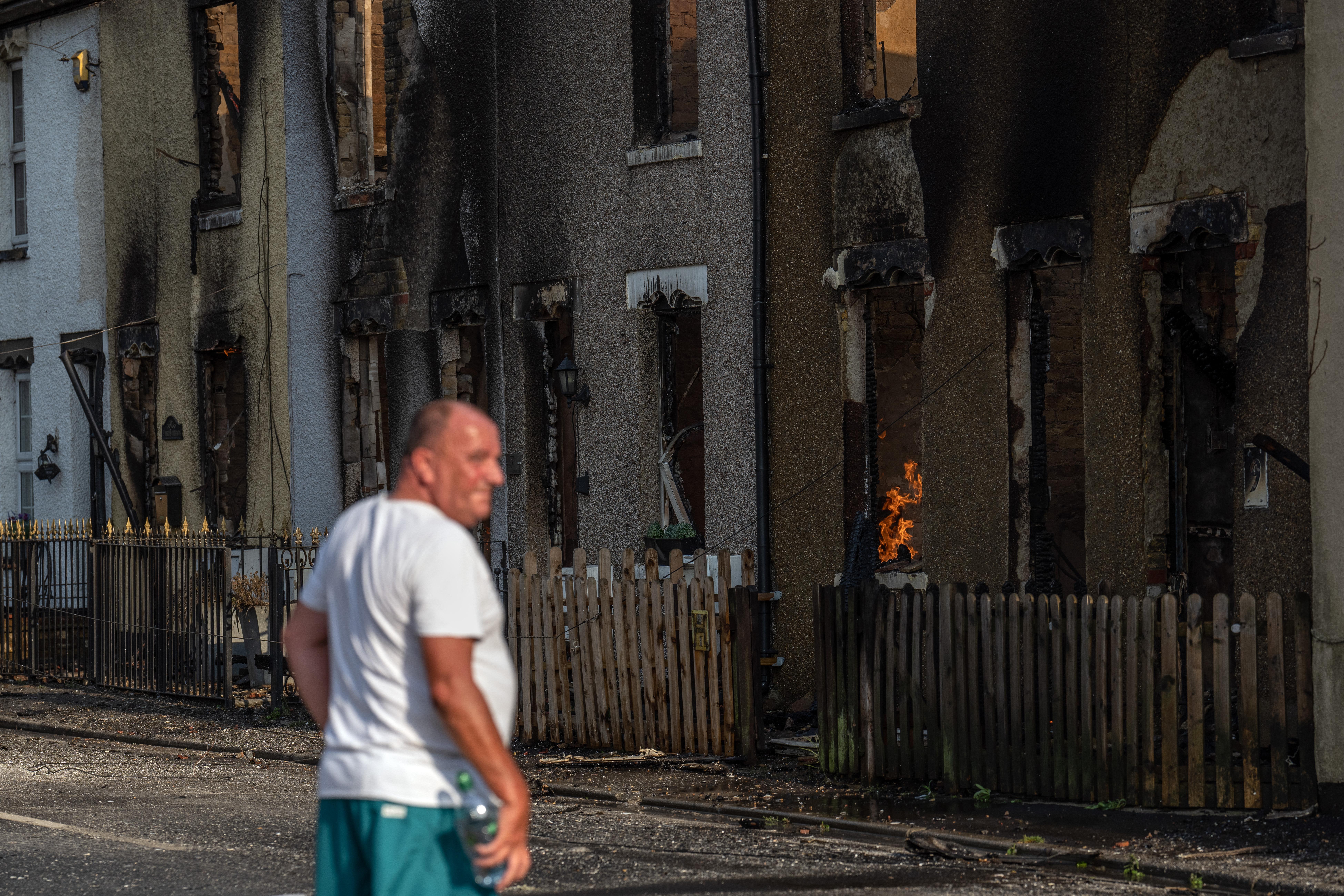 WENNINGTON, GREATER LONDON - JULY 19: A local resident pauses works next to building destroyed by fire on July 19, 2022 in Wennington, England. A series of grass fires broke out around the British capital amid an intense heatwave. (Photo by Carl Court/Getty Images)