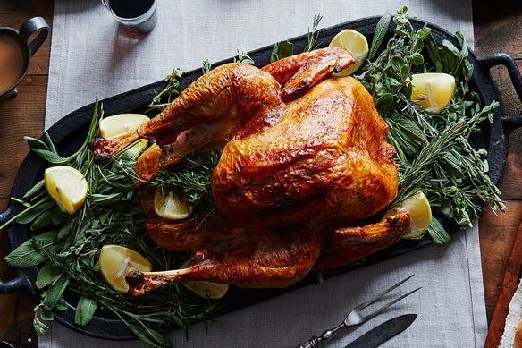 Platter of whole roasted turkey with sliced lemons over herbs